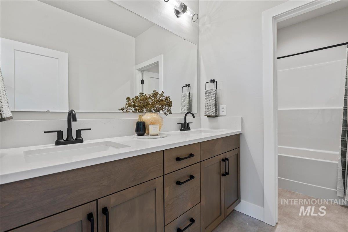 985 West Malbar Street Meridian, ID 83646 - Photo 33 of 39 Dual sink vanity featuring wood-finish cabinetry, white countertop, and matte black hardware