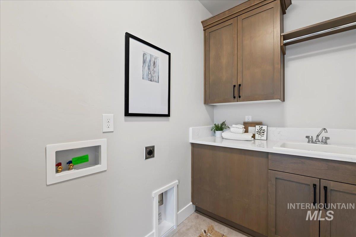 985 West Malbar Street Meridian, ID 83646 - Photo 36 of 39 Laundry area featuring custom cabinetry, a utility sink with a chrome faucet, and a light-toned countertop