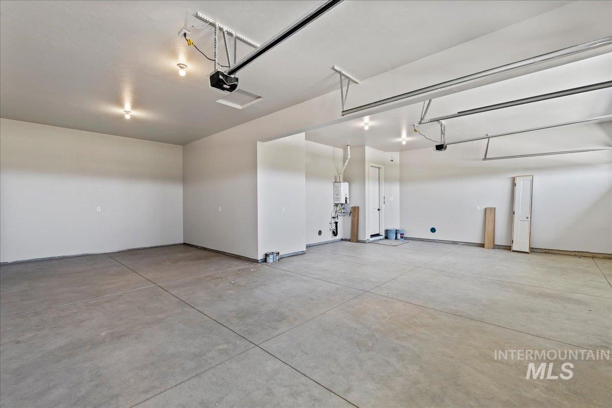 985 West Malbar Street Meridian, ID 83646 - Photo 39 of 39 Spacious garage featuring a concrete floor, white painted walls, ceiling-mounted lighting, and a visible water heater