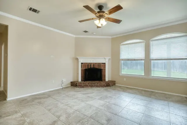 a view of an empty room with window and chandelier fan