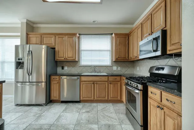 a kitchen with stainless steel appliances kitchen island granite countertop a refrigerator and a sink