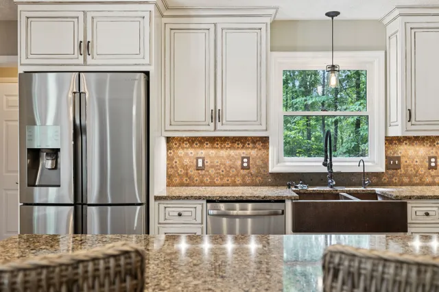 a kitchen with stainless steel appliances granite countertop a refrigerator a stove top oven a sink dishwasher a dining table and chairs with wooden floor