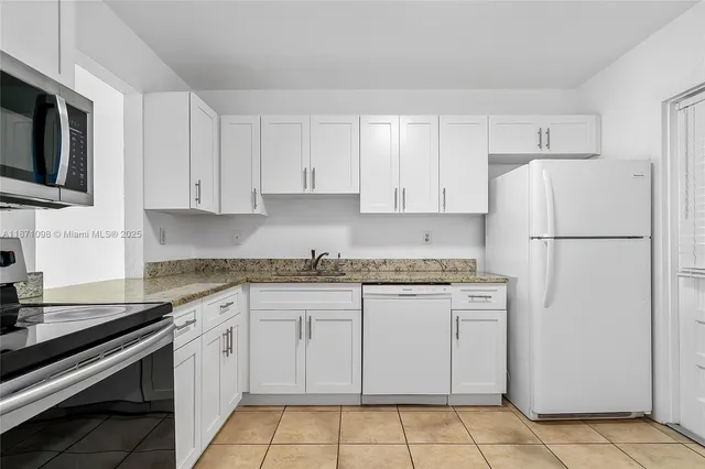 a kitchen with granite countertop white cabinets stainless steel appliances and a sink