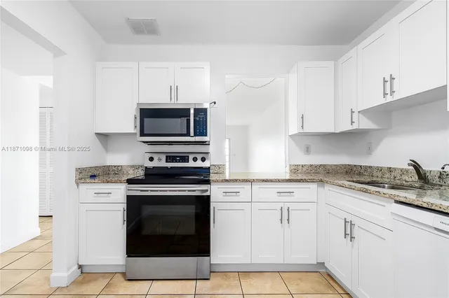 a kitchen with granite countertop white cabinets and stainless steel appliances