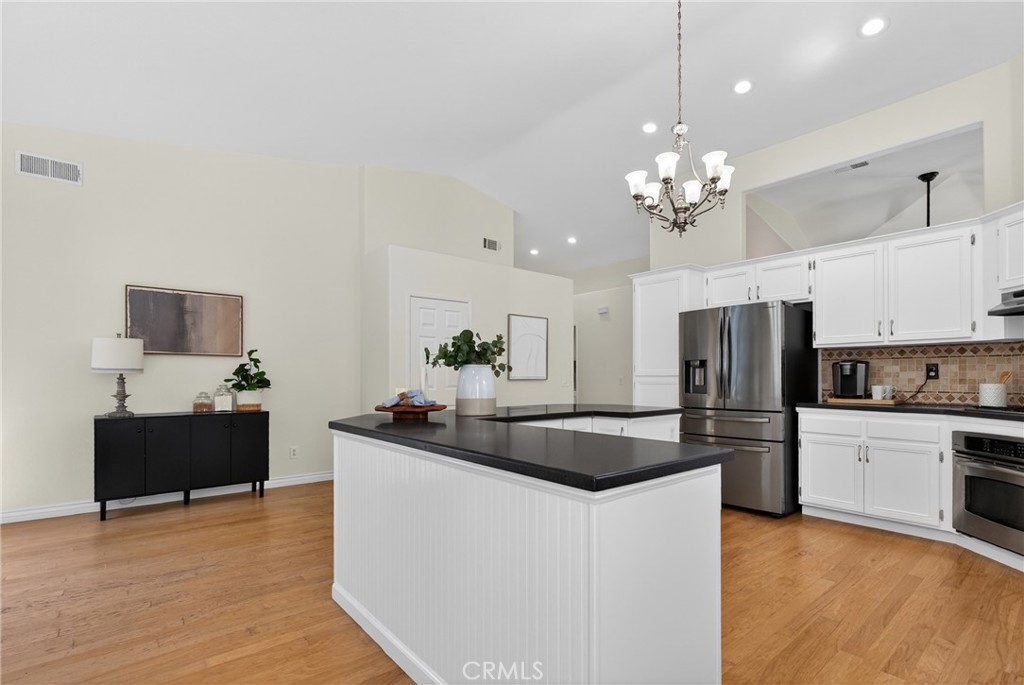 25837 Anderson Lane Stevenson Ranch, CA 91381 - Photo 11 of 22 a kitchen with kitchen island granite countertop stainless steel appliances a refrigerator a stove a sink a dining table and chairs with wooden floor