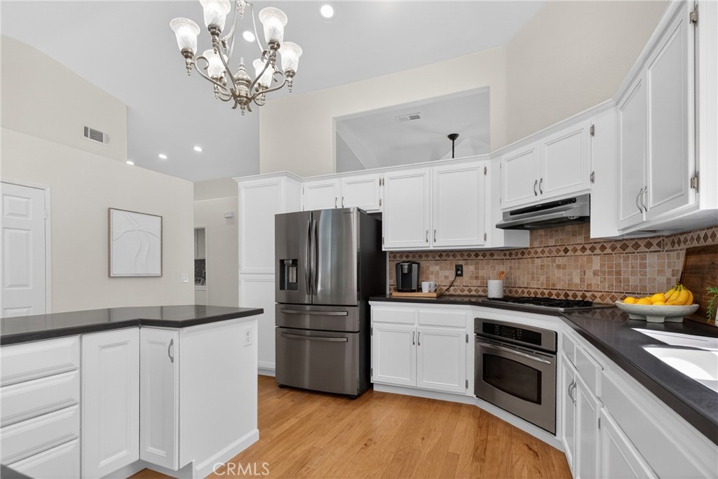 25837 Anderson Lane Stevenson Ranch, CA 91381 - Photo 12 of 22 a kitchen with stainless steel appliances granite countertop a refrigerator a sink dishwasher a stove and white cabinets with wooden floor