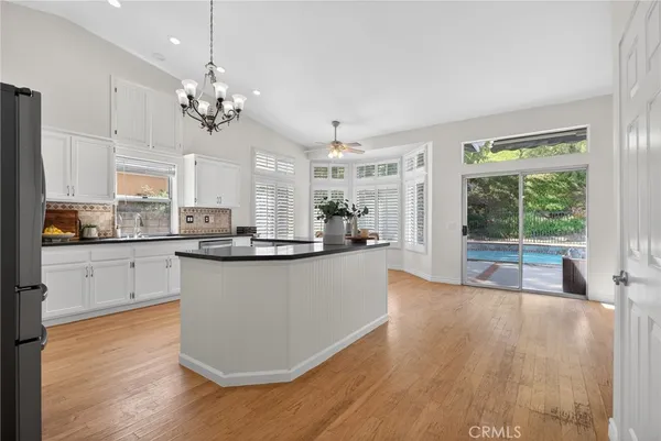 a large kitchen with kitchen island a large counter space a sink appliances and a large window