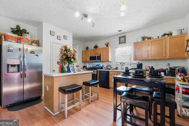 a kitchen with stainless steel appliances kitchen island granite countertop a table chairs stove and refrigerator