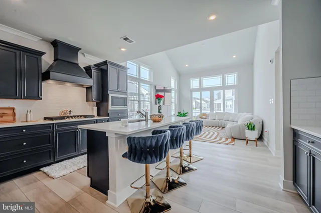 a kitchen with stainless steel appliances kitchen island granite countertop a table chairs sink and cabinets