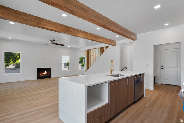 7238 South 525 East Midvale, UT 84047 - Photo 8 of 29 Open-concept living area featuring a kitchen island with a gold-finish faucet and integrated sink, exposed wood beams, wood-finish flooring, a contemporary fireplace, and recessed lighting
