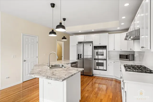 a kitchen with stainless steel appliances granite countertop a sink a stove and chairs