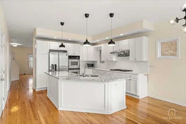 a kitchen with stainless steel appliances kitchen island granite countertop a sink stove and refrigerator