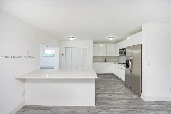 a large white kitchen with wooden floor and a sink