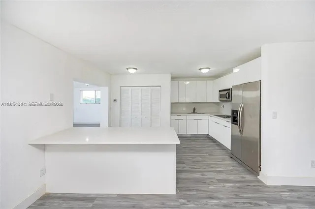 a large white kitchen with wooden floor and a sink