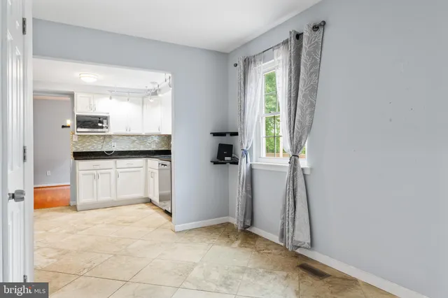 a kitchen with white cabinets and window