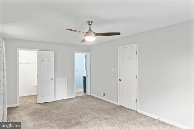 an empty room with closet and a ceiling fan