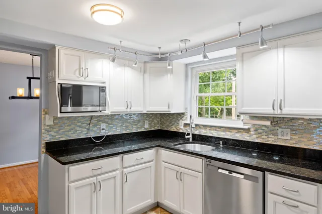 a kitchen with granite countertop a sink stainless steel appliances a window and a counter top space
