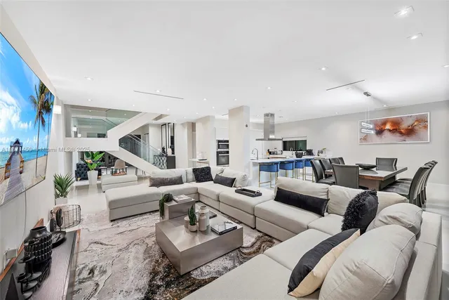 a living room with furniture kitchen view and a large window