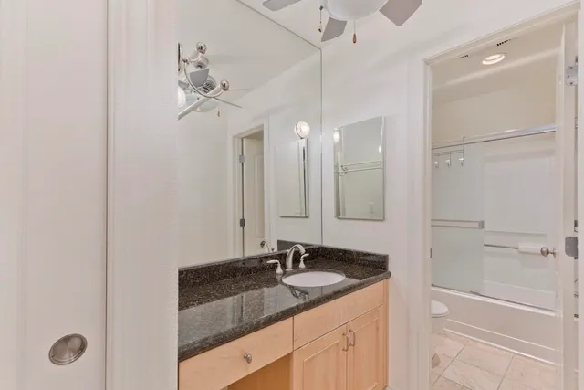 a bathroom with a granite countertop sink a mirror and a shower