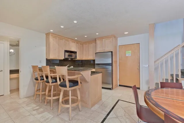 a kitchen with a dining table chairs and refrigerator