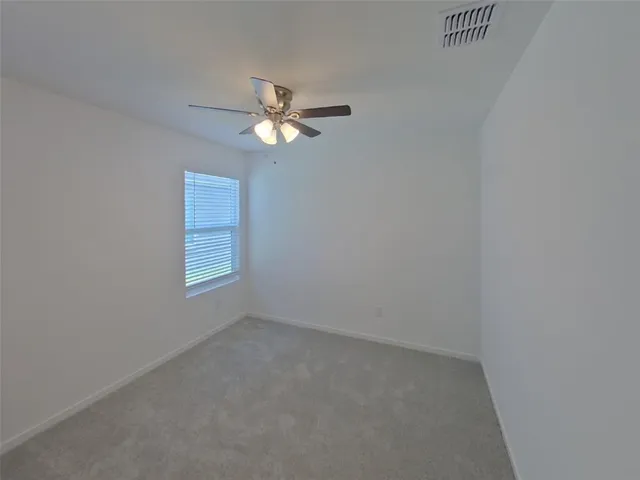 an empty room with a chandelier fan and windows
