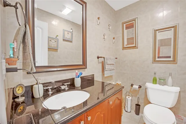 a bathroom with a granite countertop toilet sink and mirror