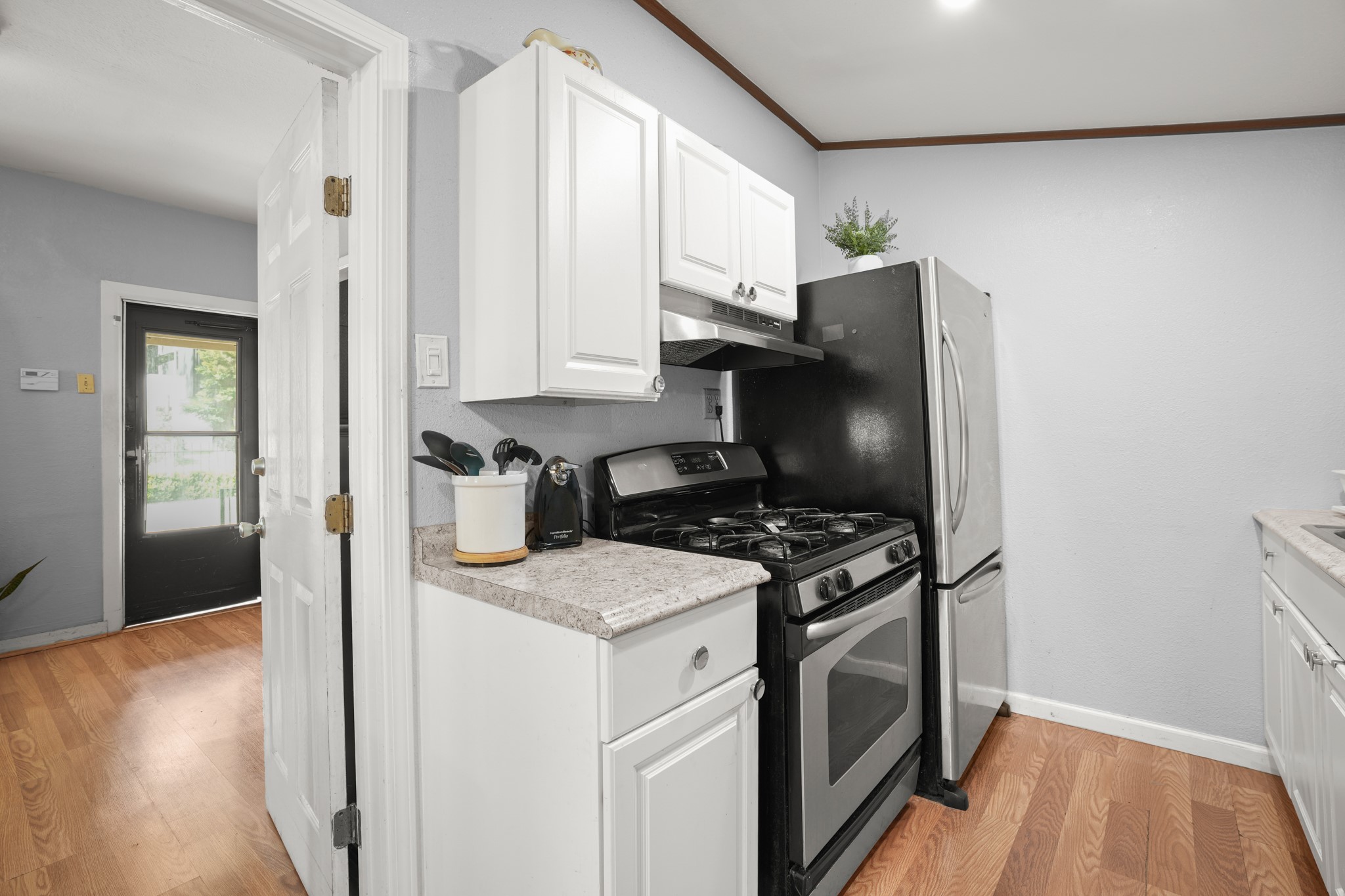 1908 Holly Street Austin, TX 78702 - Photo 9 of 22 A well-appointed kitchen features white cabinetry, granite-style countertops, and hardwood flooring.