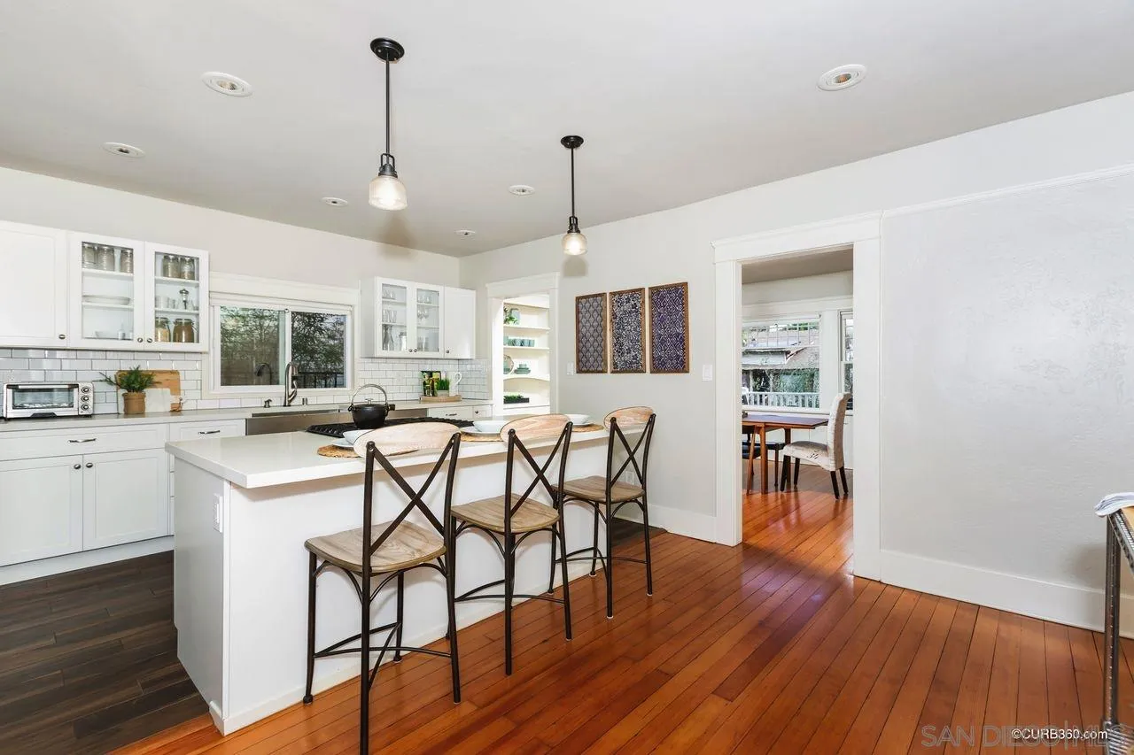 4112 Jackdaw Street San Diego, CA 92103 - Photo 10 of 34 a kitchen with stainless steel appliances granite countertop a stove top oven a refrigerator a dining table and chairs with wooden floor
