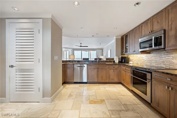 a large kitchen with stainless steel appliances granite countertop a stove top oven a sink dishwasher and a refrigerator