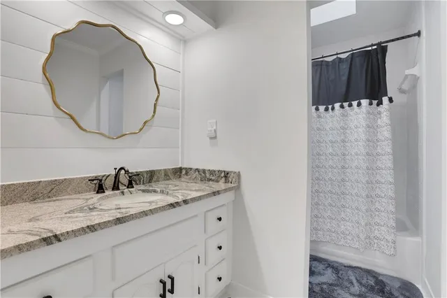a bathroom with a granite countertop sink a mirror and shower