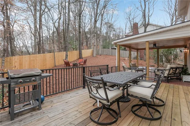 a view of a patio with table and chairs with wooden floor and fence