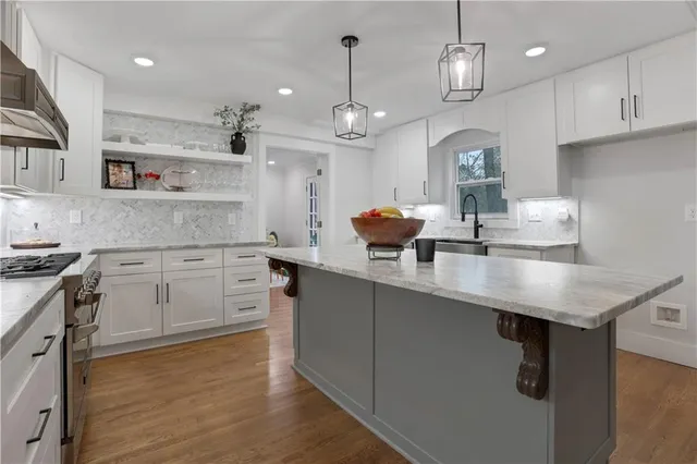 a kitchen with stainless steel appliances granite countertop a sink a stove and a wooden floors