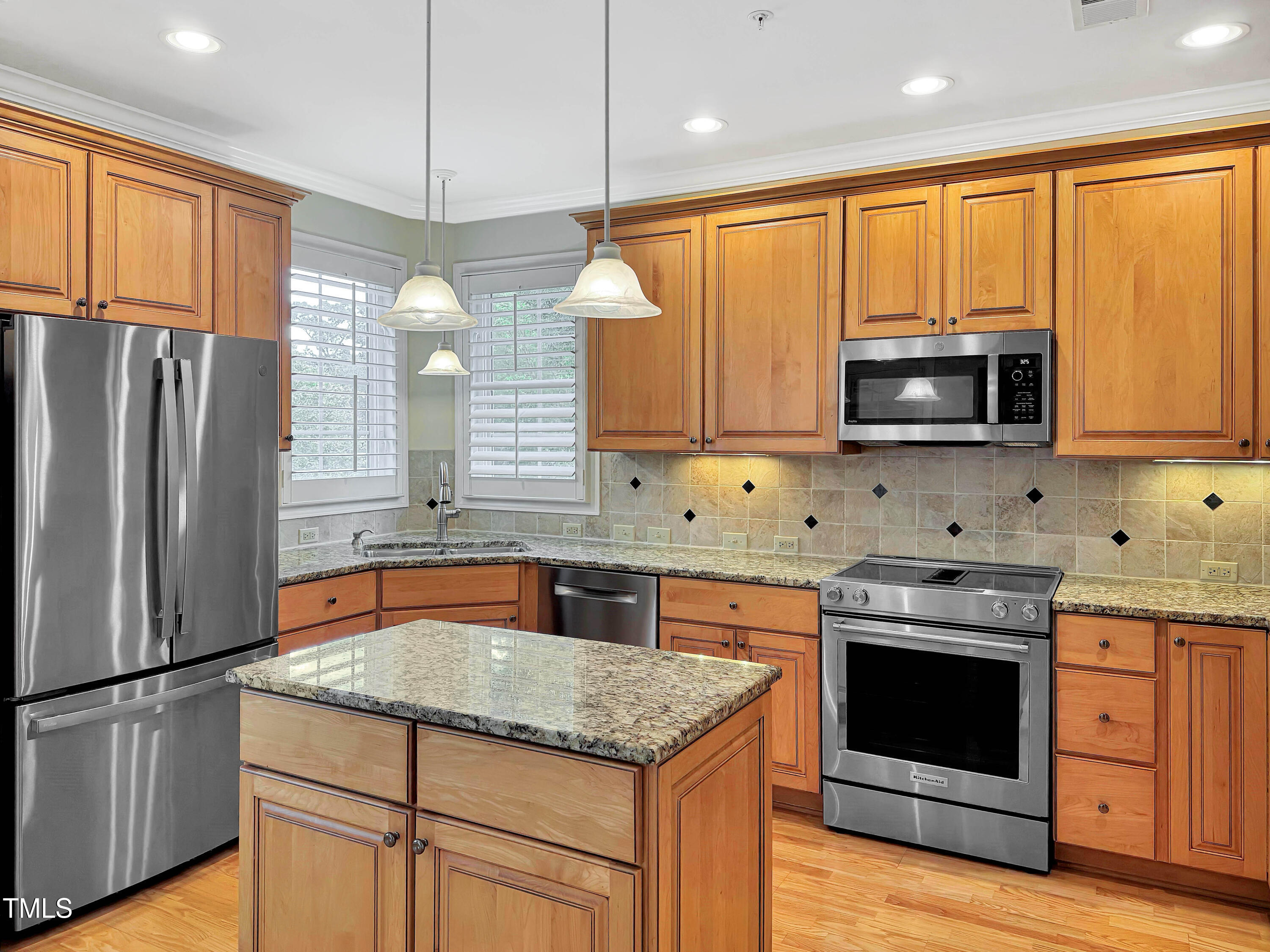 3700 Baron Cooper Pass, Unit 302 Raleigh, NC 27612 - Photo 26 of 67 a kitchen with stainless steel appliances granite countertop a stove top oven a refrigerator and a sink with wooden cabinets