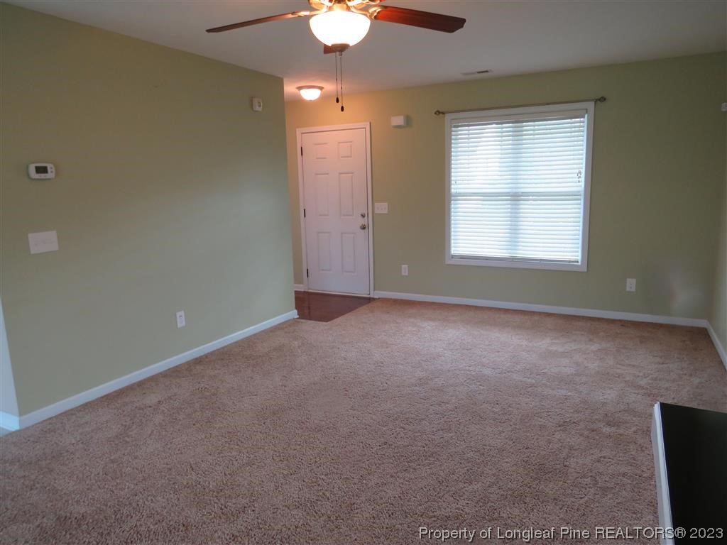 44 Archer Drive Bunnlevel, NC 28323 - Photo 3 of 10 an empty room with a chandelier fan and windows