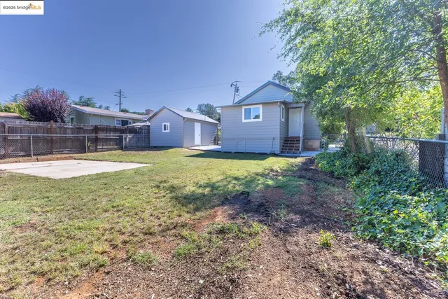 a view of a house with a yard and large trees