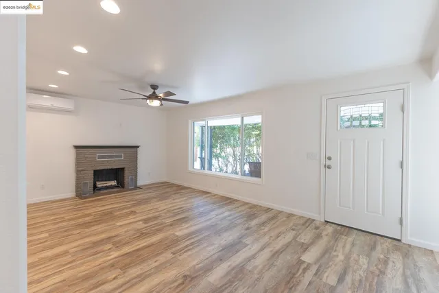 a view of an empty room with a window and fireplace