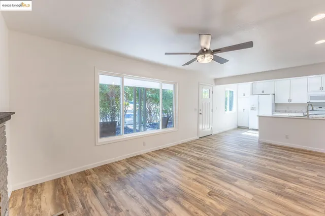 a view of an empty room with a kitchen and wooden floor