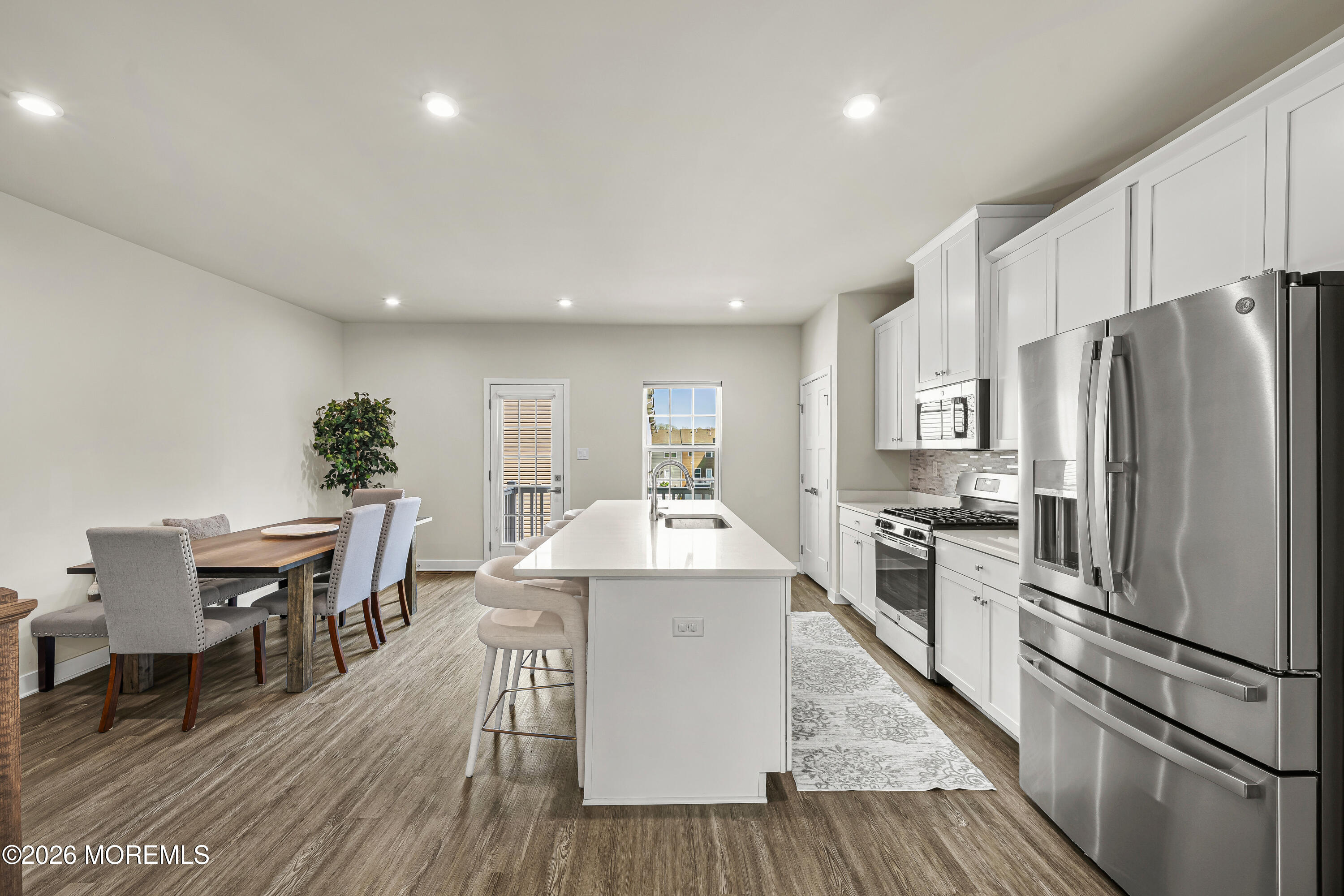 1306 English Lane, Unit 1306 Parlin, NJ 08859 - Photo 13 of 41 a kitchen with stainless steel appliances a dining table chairs stove refrigerator and cabinets