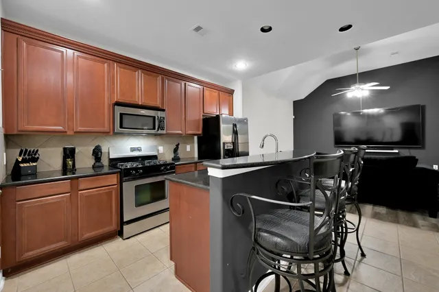 a kitchen with stainless steel appliances granite countertop a stove top oven a sink dishwasher a dining table and chairs with wooden floor