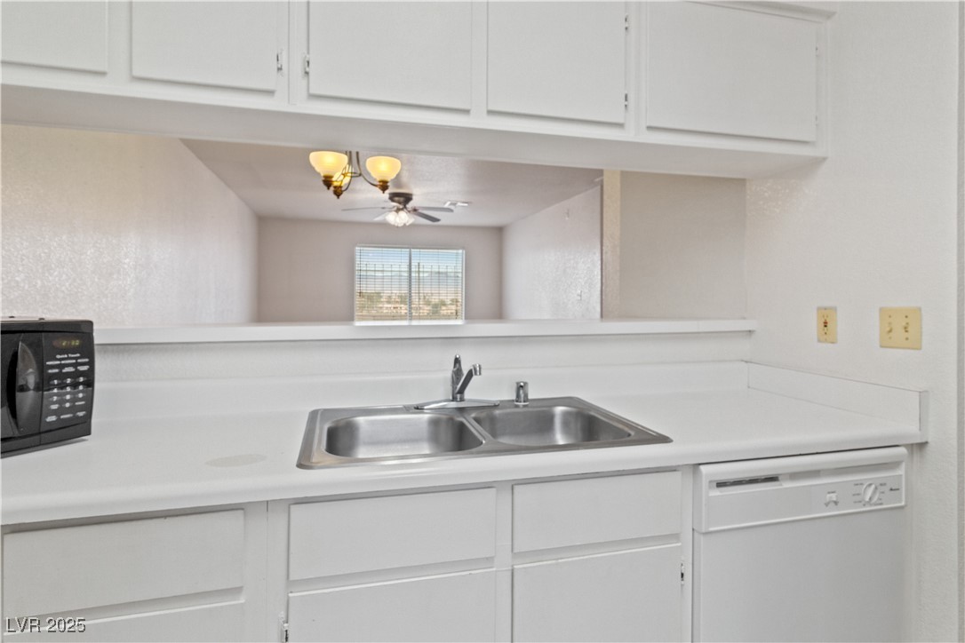 2036 Mesquite Lane, Unit 103 Laughlin, NV 89029 - Photo 11 of 67 Kitchen featuring light countertops, white cabinets, a sink, black microwave, and white dishwasher