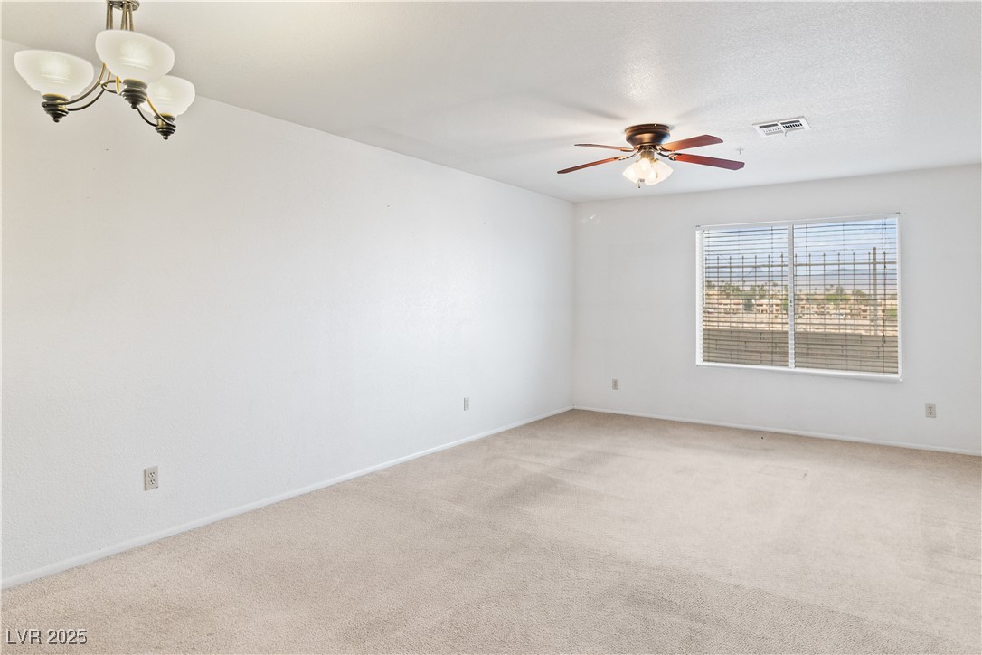 2036 Mesquite Lane, Unit 103 Laughlin, NV 89029 - Photo 13 of 67 Empty room featuring a textured ceiling, visible vents, baseboards, ceiling fan with notable chandelier, and light colored carpet