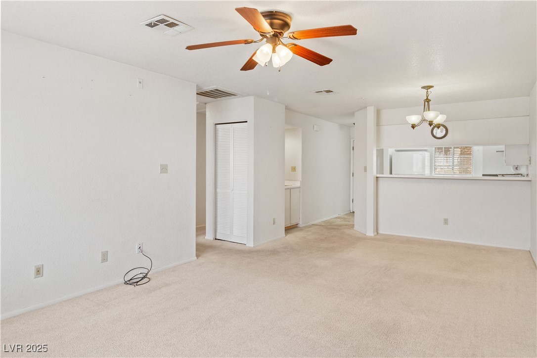 2036 Mesquite Lane, Unit 103 Laughlin, NV 89029 - Photo 16 of 67 Unfurnished living room with visible vents, ceiling fan with notable chandelier, and light colored carpet