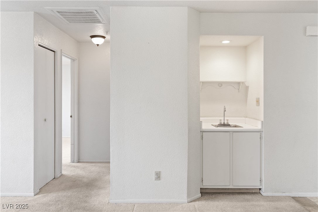 2036 Mesquite Lane, Unit 103 Laughlin, NV 89029 - Photo 18 of 67 Hall featuring a sink, baseboards, light colored carpet, and visible vents