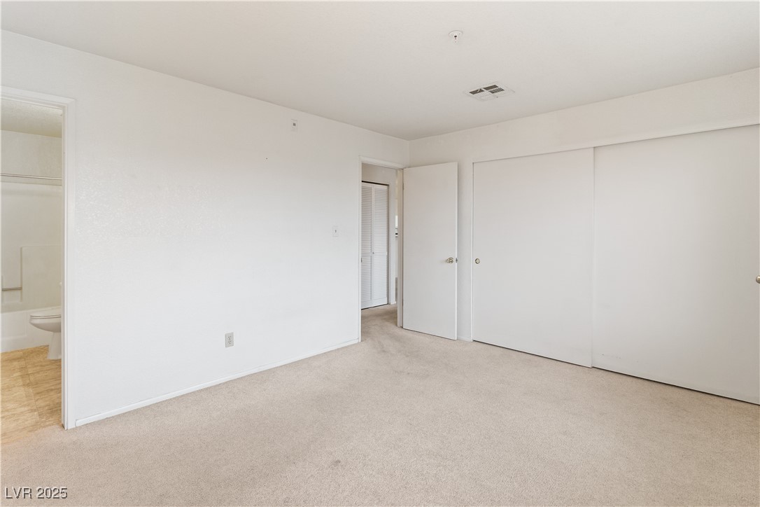 2036 Mesquite Lane, Unit 103 Laughlin, NV 89029 - Photo 22 of 67 Unfurnished bedroom featuring a closet, ensuite bathroom, baseboards, visible vents, and carpet
