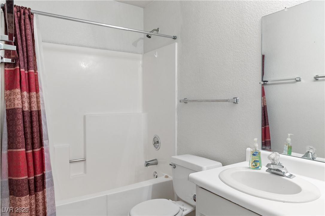 2036 Mesquite Lane, Unit 103 Laughlin, NV 89029 - Photo 29 of 67 Bathroom featuring toilet, vanity, a textured wall, and shower / tub combo