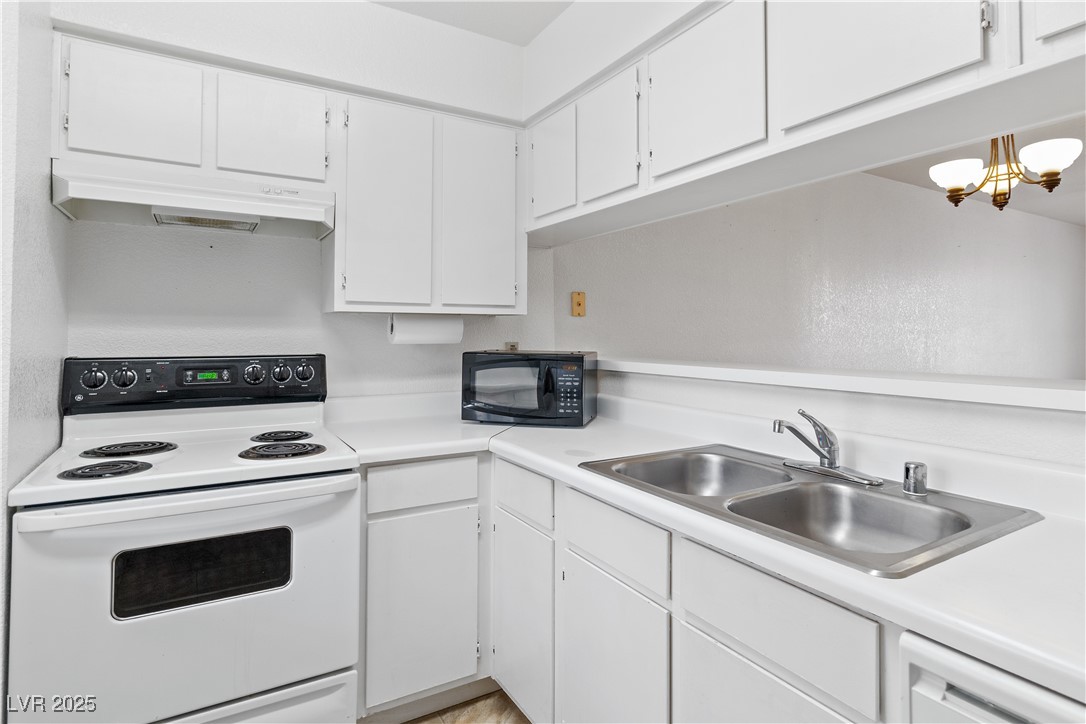 2036 Mesquite Lane, Unit 103 Laughlin, NV 89029 - Photo 8 of 67 Kitchen with light countertops, a sink, under cabinet range hood, white appliances, and white cabinets