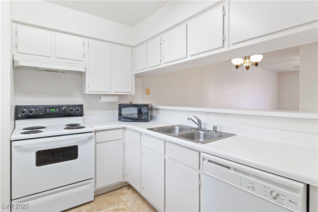 2036 Mesquite Lane, Unit 103 Laughlin, NV 89029 - Photo 9 of 67 Kitchen featuring light countertops, a sink, white cabinetry, under cabinet range hood, and white appliances