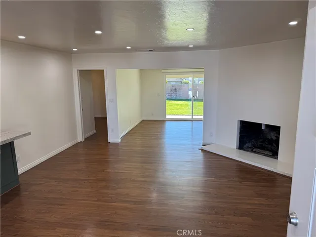 an empty room with wooden floor and a fireplace