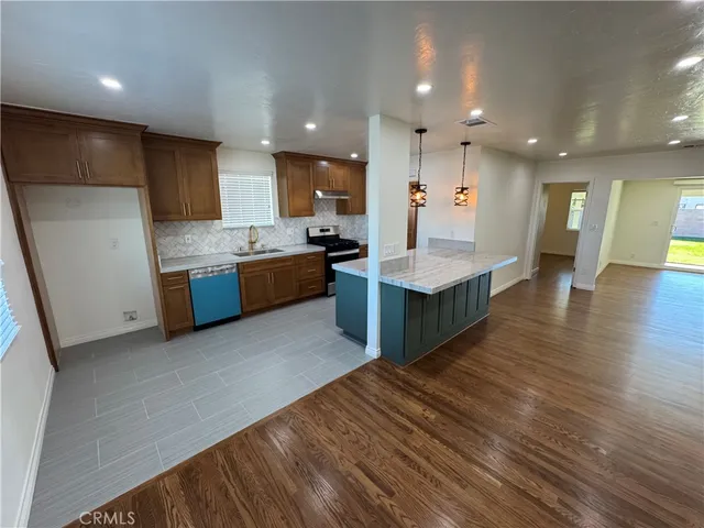 a large kitchen with stainless steel appliances granite countertop a large counter top a sink dishwasher and a refrigerator