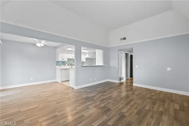 a view of an empty room with window and wooden floor